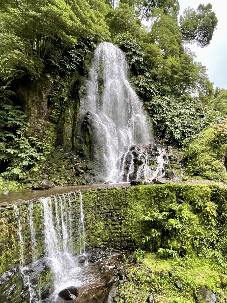 Waterfall cascading over mossy stone walls in a lush green valley
