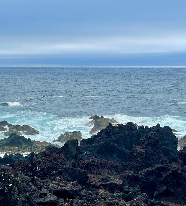 Turquoise waves breaking on black volcanic rocks