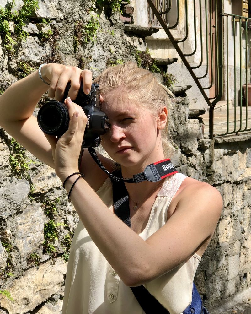 Travel creator photographing with a camera against an old stone wall