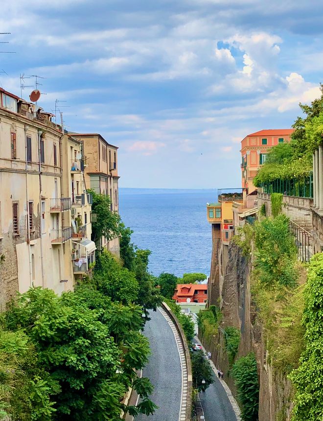 Street in Sorrento framing a view of the Mediterranean Sea between cliffside buildings
